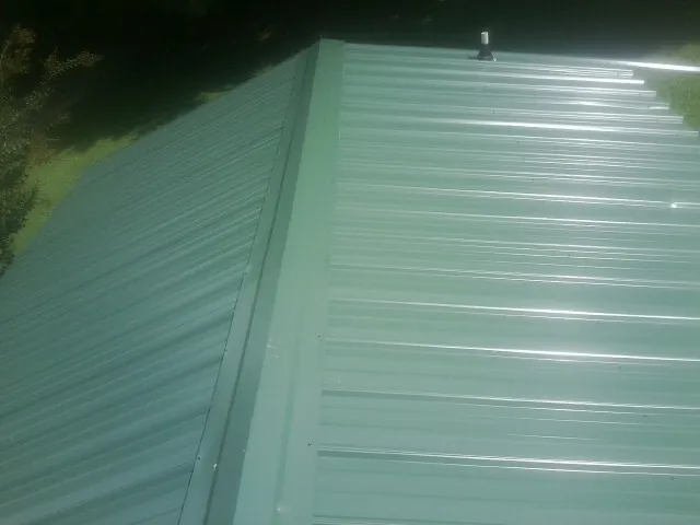 New green metal panels meeting at the ridge of a roof — Flat Roof Repair work by our crew in San Miguel