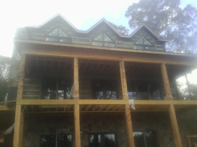 Dormers and porch framing on a large log home under construction — Roof Coating work by our crew in San Miguel
