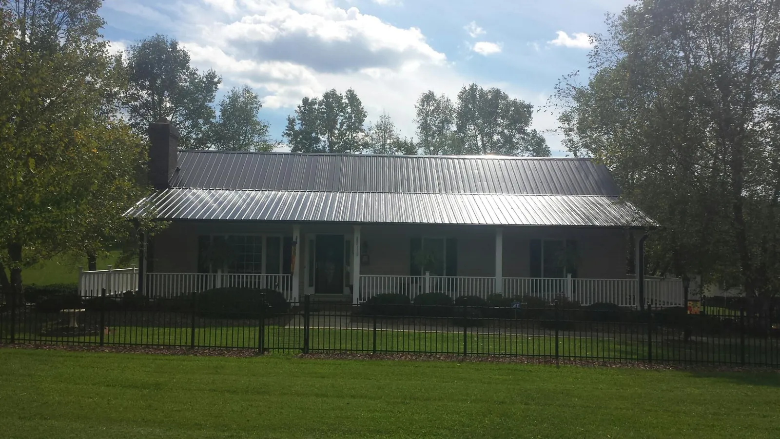 Gray metal roof on a brick ranch with a full width front porch — Gutter Guard Installation work by our crew in San Miguel