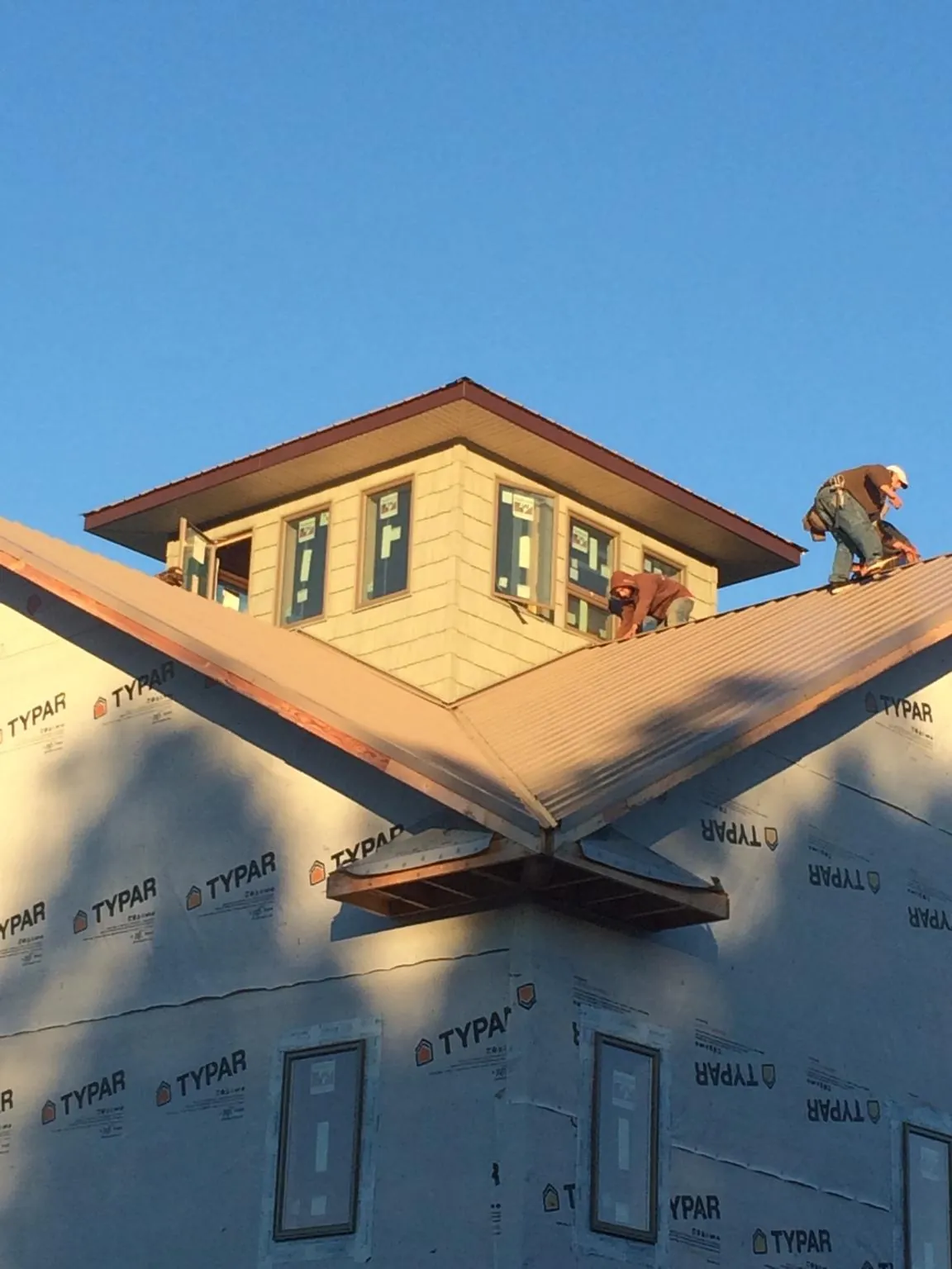 Roofers working around a rooftop cupola on a new metal roof at sunset — Roof Waterproofing in San Miguel by Roofing Brothers